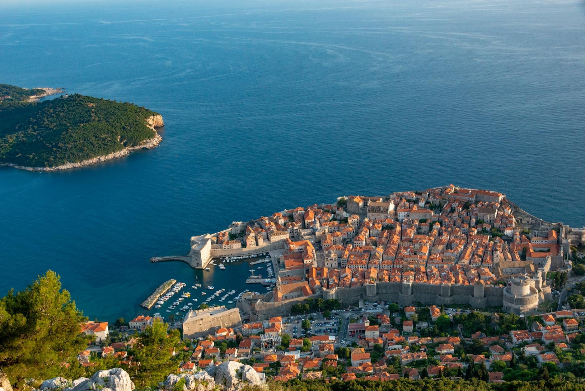 Vista panorámica sobre la Ciudad Vieja amurallada de Dubrovnik, con históricos edificios de piedra caliza, tejados rojos y el profundo mar Adriático azul.
