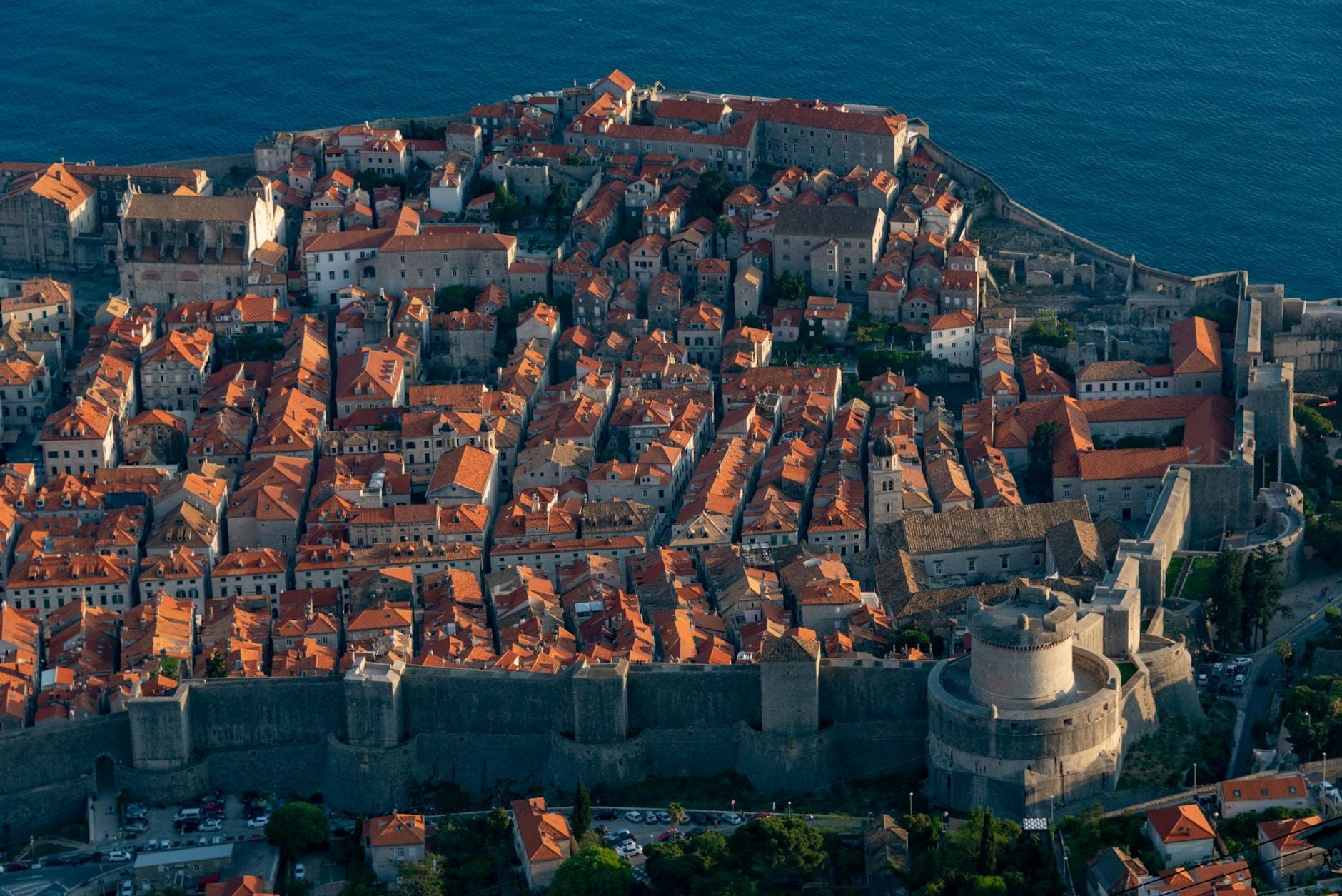 Vista aérea del casco antiguo histórico de Dubrovnik con sus murallas de piedra y tejados naranjas junto al mar Adriático.