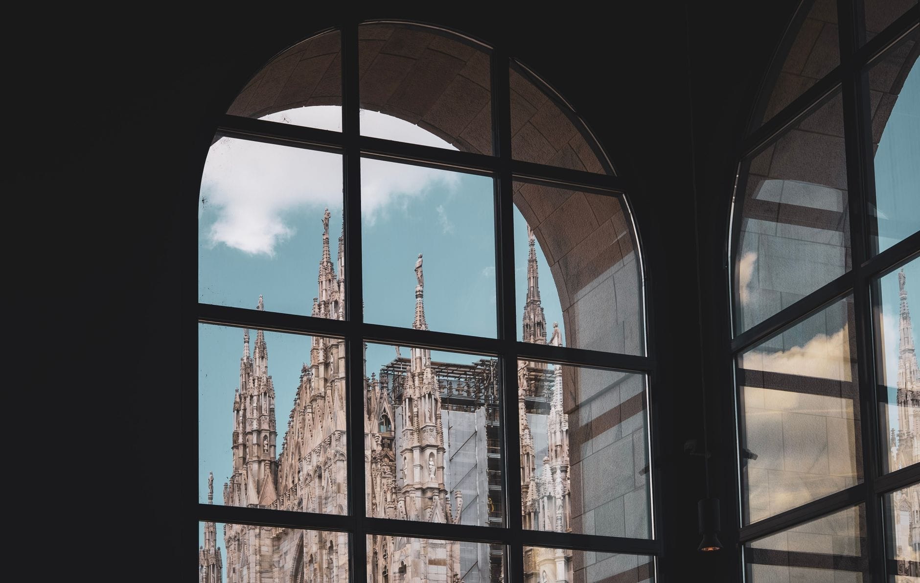 Le guglie della Cattedrale di Milano viste attraverso le grandi finestre ad arco del museo, dove i dettagli gotici del Duomo si fondono con la quiete degli interni.