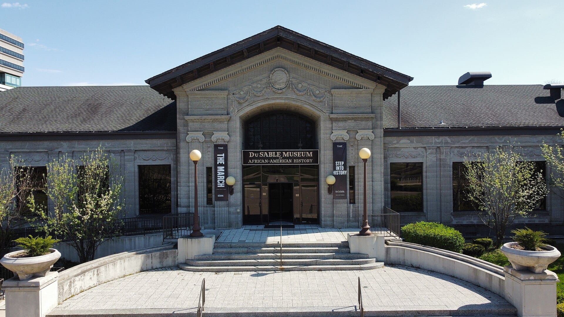 Ingresso principale del DuSable Museum of African-American History con architettura classica in pietra, gradini curvi e paesaggistica verde in una giornata serena.