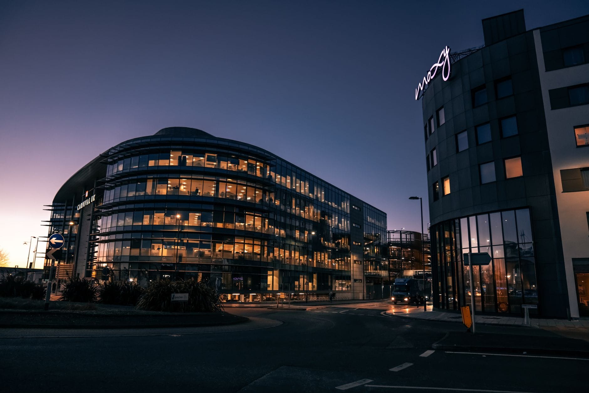 Moderni edifici alberghieri accanto a una strada aeroportuale al crepuscolo, incluso un edificio con l'insegna 'Moxy' vicino all'Edinburgh Airport.