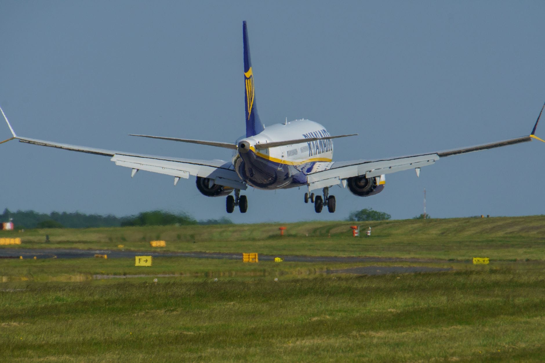 Ein Ryanair-Passagierjet landet auf der grünen Landebahn des Flughafens Edinburgh – von hinten aufgenommen, mit klarem Himmel und sichtbaren Markierungen auf dem Rollfeld.