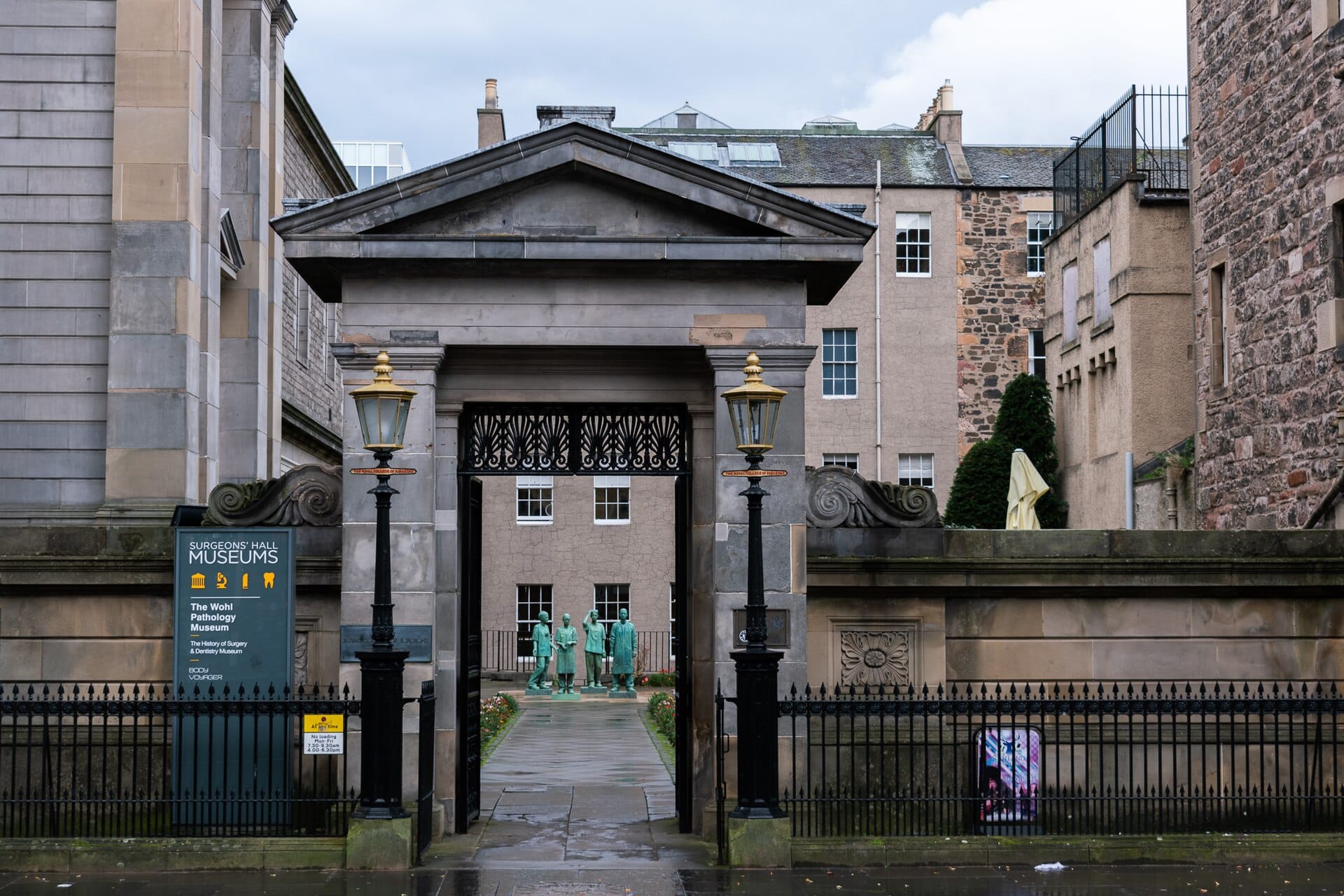 Eingang zu den Surgeons' Hall Museums in Edinburgh, mit historischem Steintor, Lampen und Statuen von Chirurgen im Innenhof.