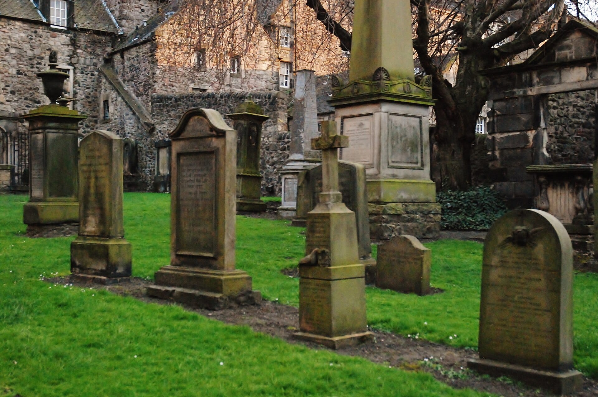 Antiche lapidi e grandi monumenti in pietra a Greyfriars Kirkyard, con edifici in pietra sullo sfondo a Edimburgo.