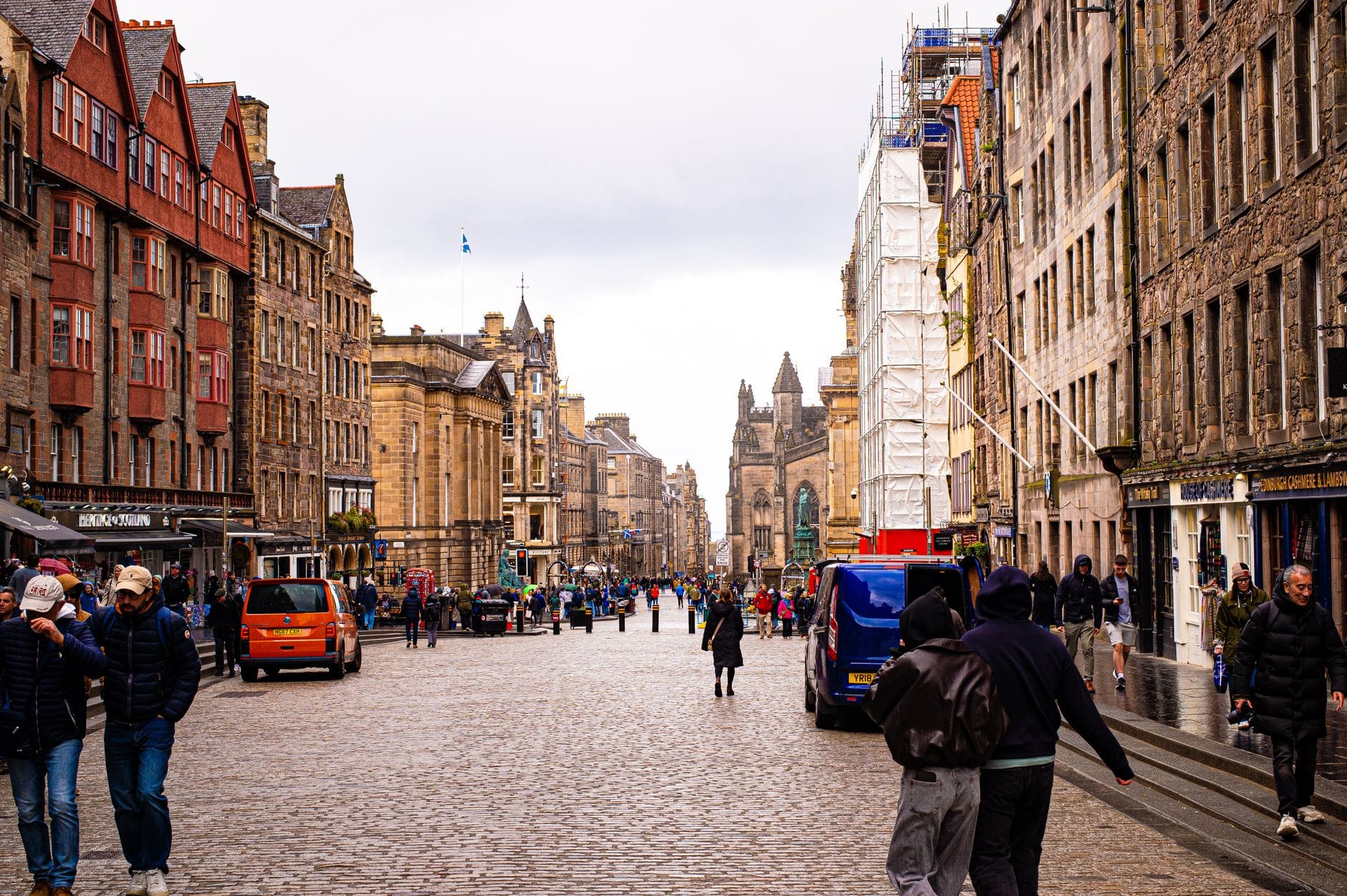 Weitwinkelansicht der Royal Mile in Edinburgh mit Spaziergängern, historischen Steingebäuden auf beiden Seiten und laufenden Festivalvorbereitungen.