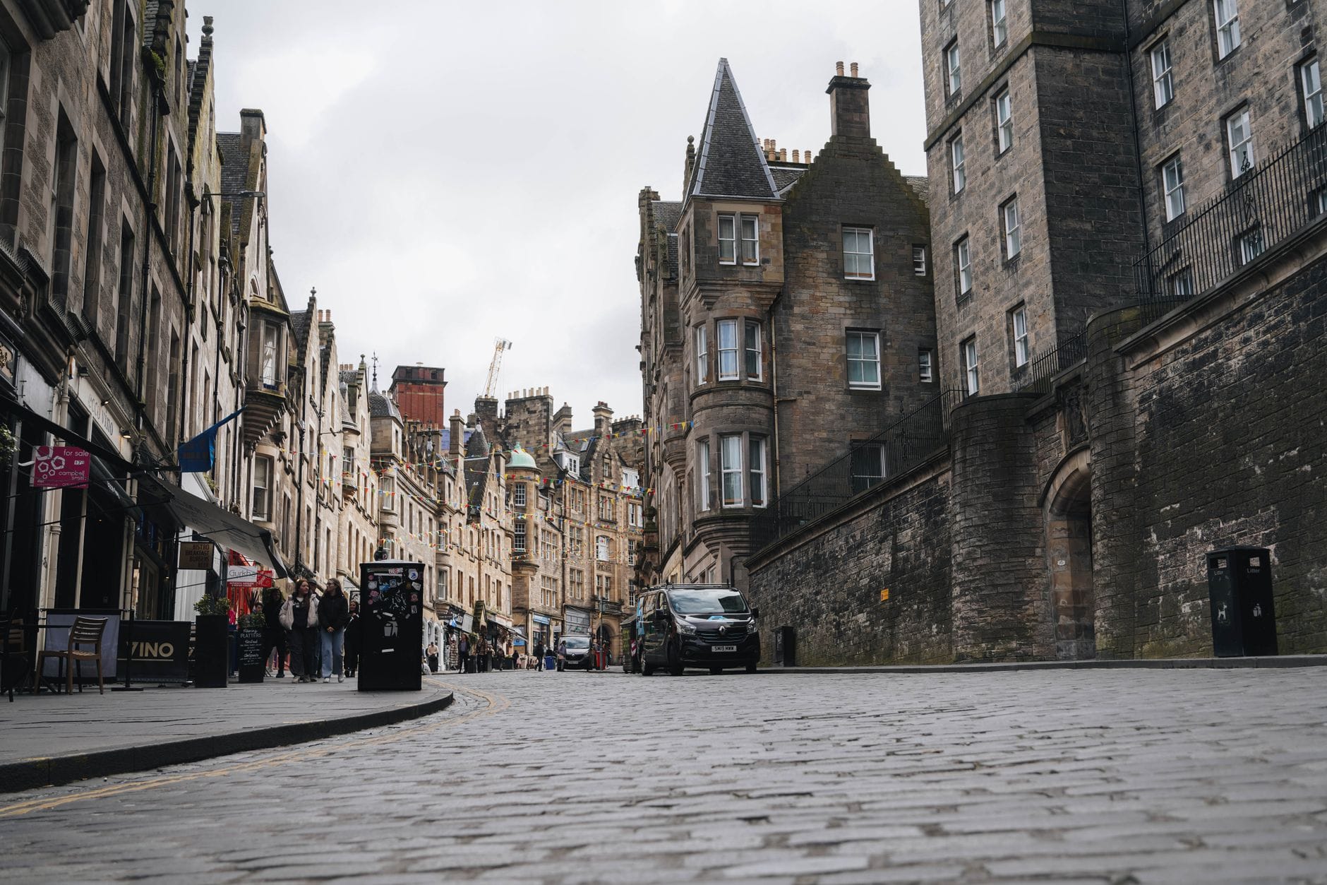 Strada acciottolata nell'Old Town di Edimburgo con pedoni ed edifici storici in pietra su entrambi i lati, ideale per passeggiare.