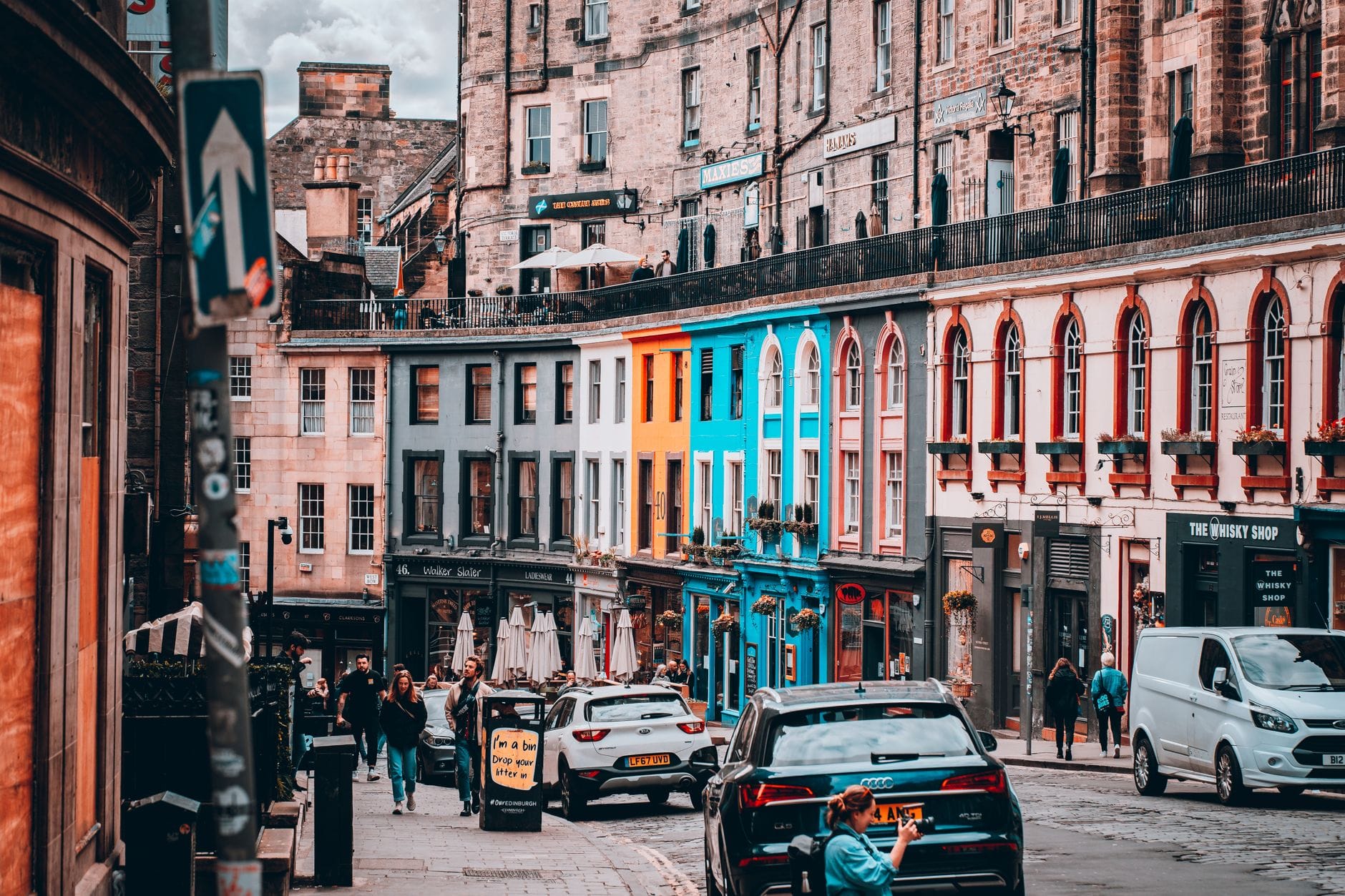 Die Victoria Street in Edinburgh mit bunten unabhängigen Geschäften, Passanten auf dem Gehweg und historischen Steingebäuden – ein lebendiges Bild von Edinburghs bestem Einkaufsviertel.