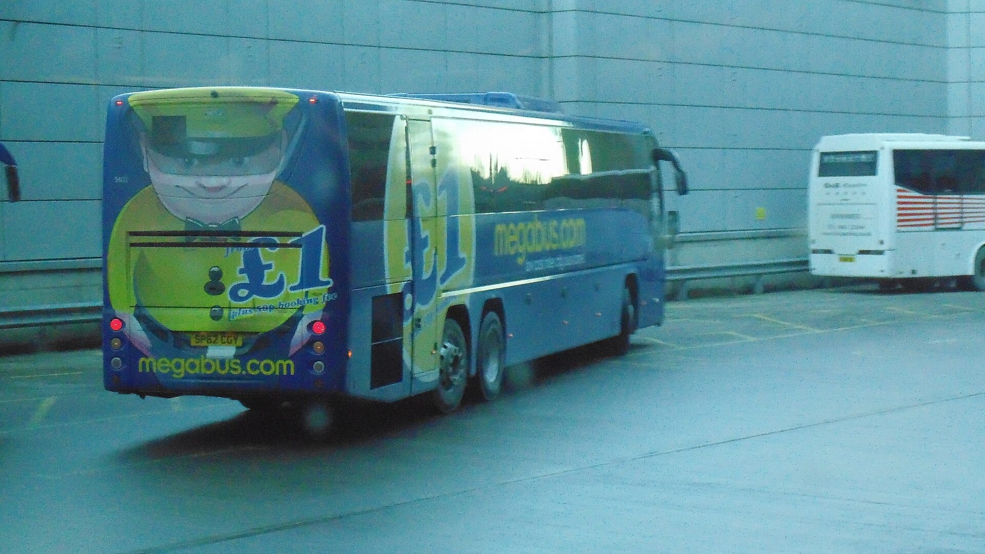 Ein Megabus-Reisebus am Busbahnhof Edinburgh, mit 'megabus.com' und Fahrpreiswerbung auf der Rückseite.