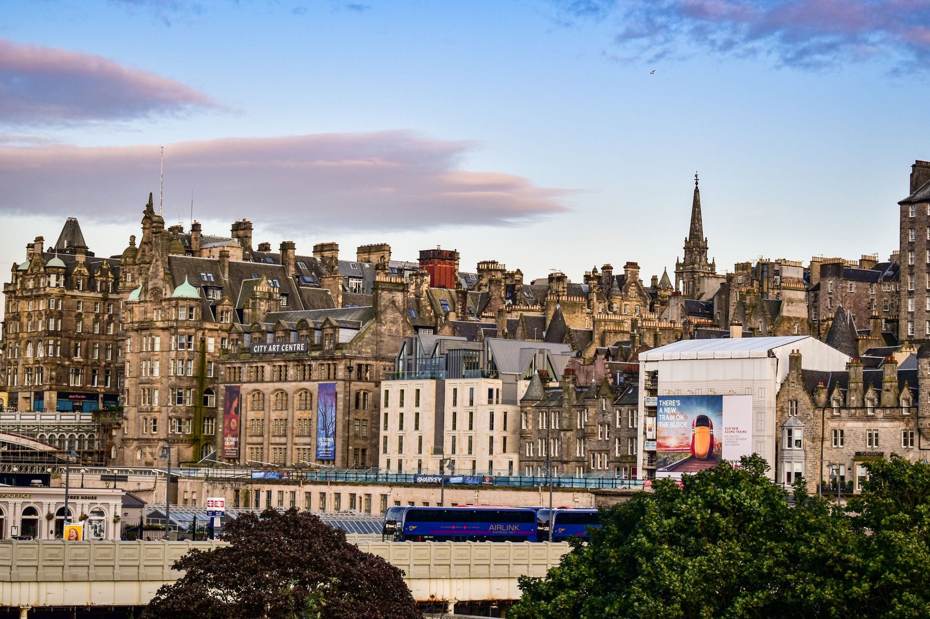 Panoramablick auf die Altstadt von Edinburgh mit historischen Gebäuden und einem Zug darunter – der klassische Auftakt für die Reise nach Inverness.