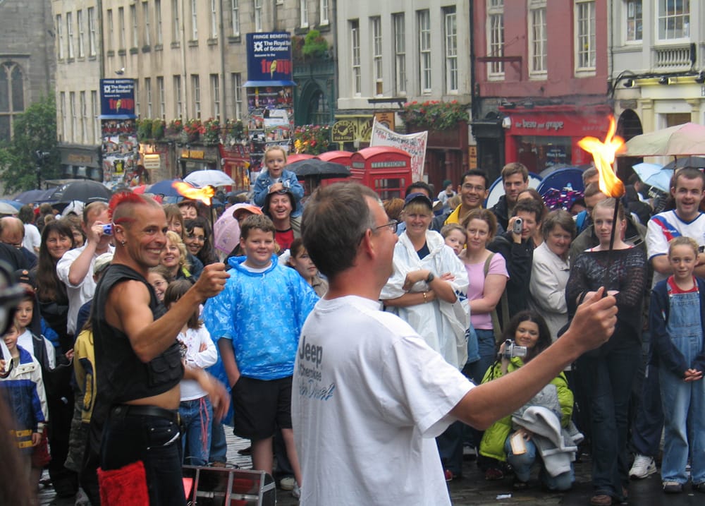 Artisti di strada che intrattengono una folla, inclusi bambini, durante l'Edinburgh Fringe Festival sulla Royal Mile