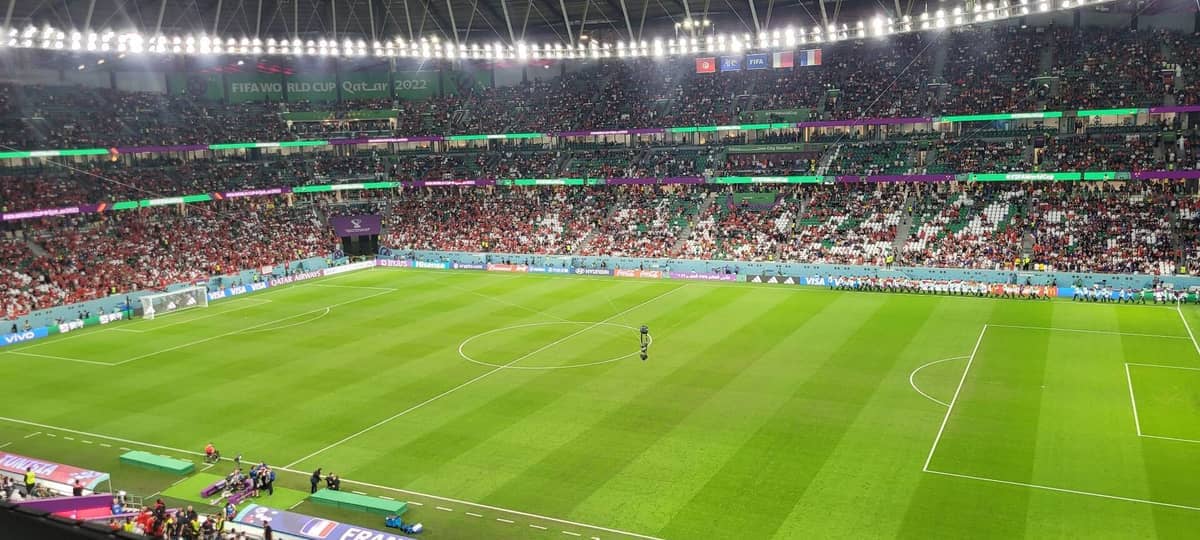Weite Ansicht des Education City Stadium voller Fans während eines FIFA-Weltmeisterschaft-Fußballspiels, unter hellen Stadionlichtern und lebhaften Sitzreihen.