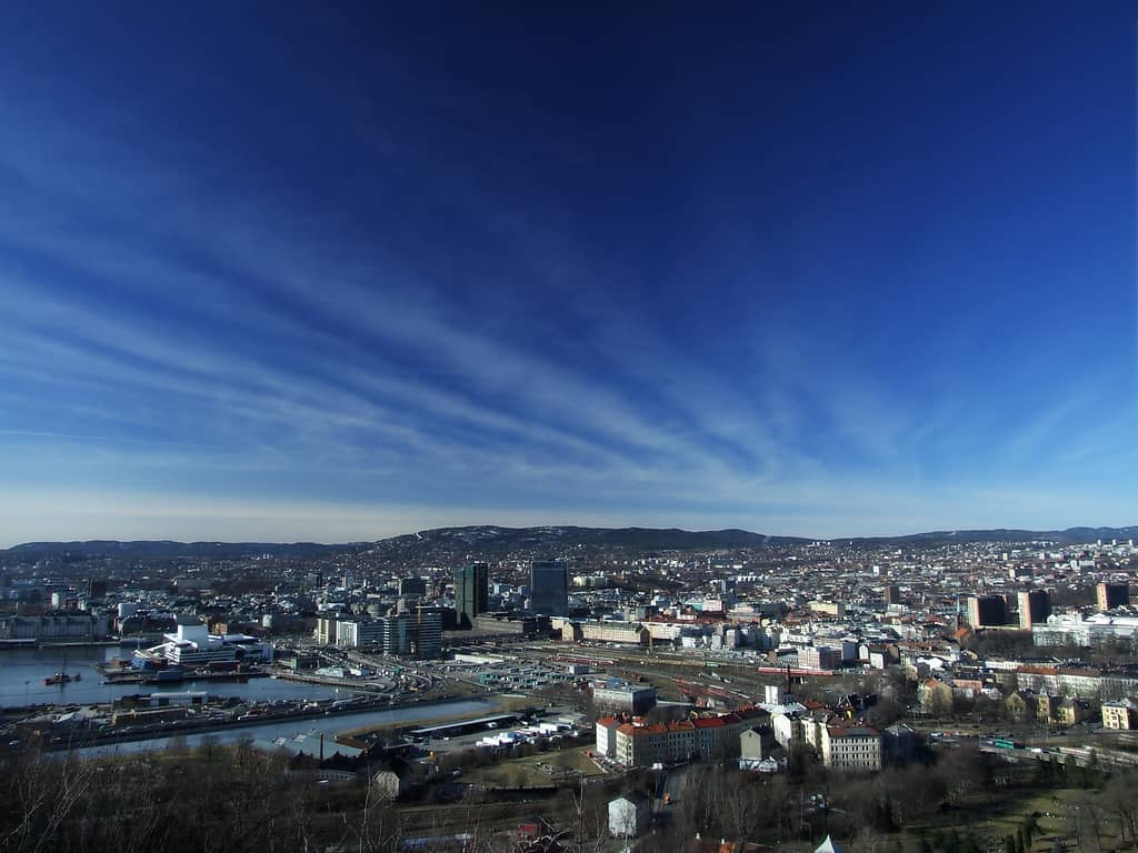 วิวพาโนรามาของเมือง Oslo ที่กว้างไกลจาก Ekeberg Viewpoint พร้อมอาคารสมัยใหม่ ท่าเรือ และท้องฟ้าสีฟ้าที่สวยงาม