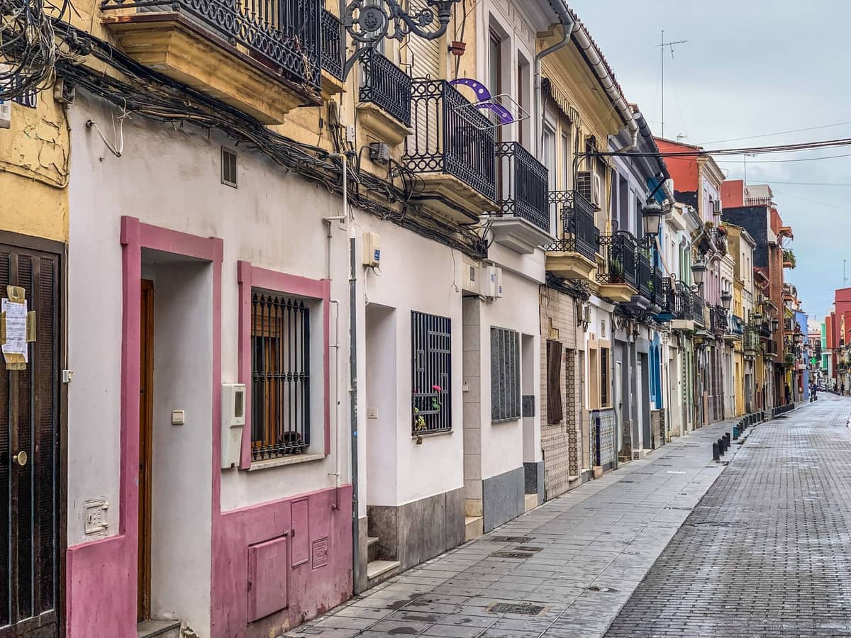 Facciate colorate a piastrelle e balconi in ferro battuto costeggiano una stretta e tranquilla via di El Cabanyal, lo storico quartiere costiero di Valencia.