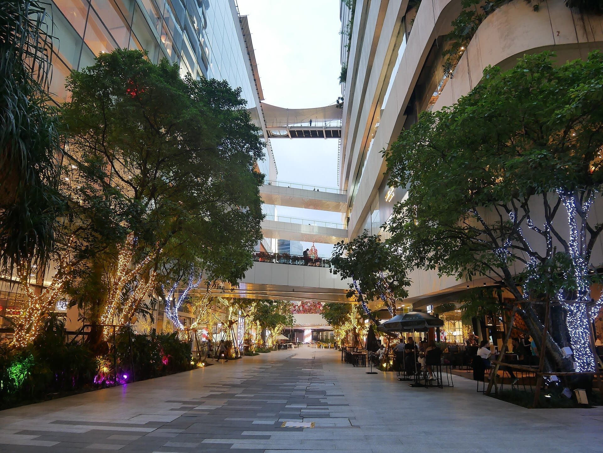 Centro commerciale EmQuartier a Bangkok con passerella all'aperto, vegetazione e terrazze su più livelli al tramonto