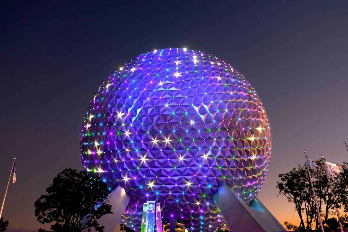 EPCOTs geodätische Kugel Spaceship Earth beleuchtet mit bunten Lichtern in der Dämmerung, mit einem klaren Abendhimmel im Hintergrund.