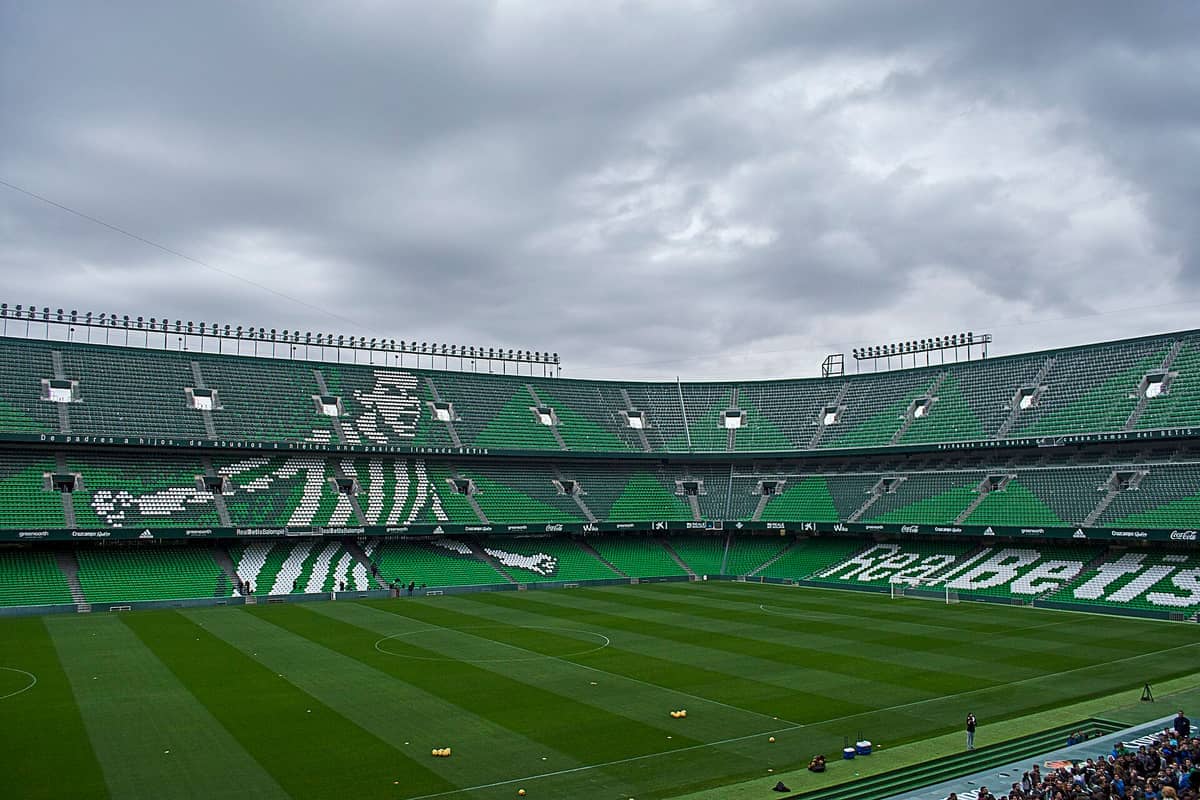 มุมมองกว้างของอัฒจันทร์สีเขียวและขาวของ Estadio Benito Villamarín สนามที่ว่างเปล่า และท้องฟ้าที่มีเมฆครึ้มในเมืองเซบียา ประเทศสเปน