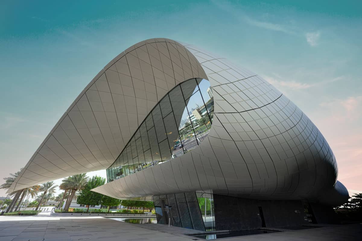 Weitwinkelaufnahme der modernen, geschwungenen Fassade des Etihad Museums mit Palmen und blauem Himmel in Dubai, Vereinigte Arabische Emirate.