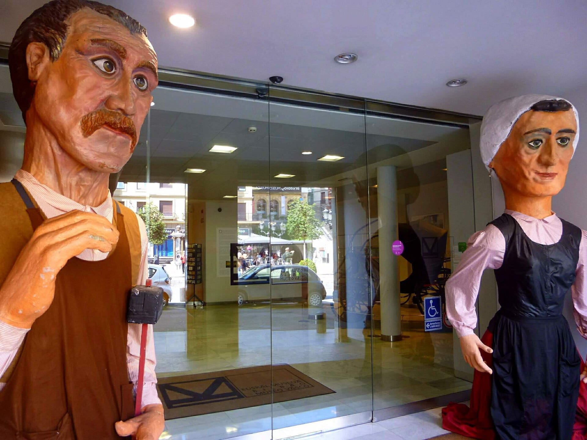 Entrance of Euskal Museoa in Bilbao featuring two large Basque traditional festival figures on display by the glass doors.