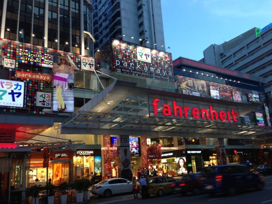Exterior view of Fahrenheit 88 shopping mall in Bukit Bintang, featuring illuminated signs, colorful advertisements, and busy street traffic in the evening.