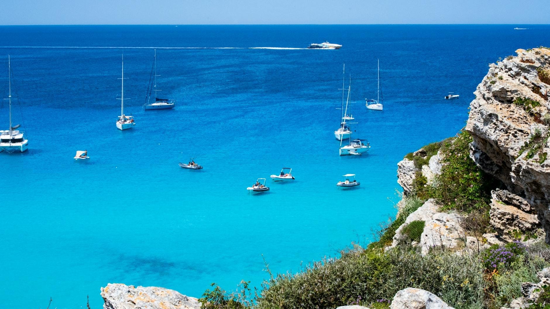 Ein atemberaubender Blick auf Favignanas türkisfarbenes Meer mit verstreuten Segelbooten und Felsklippen – ein perfektes Bild der Küstenreize und mediterranen Schönheit der Insel.