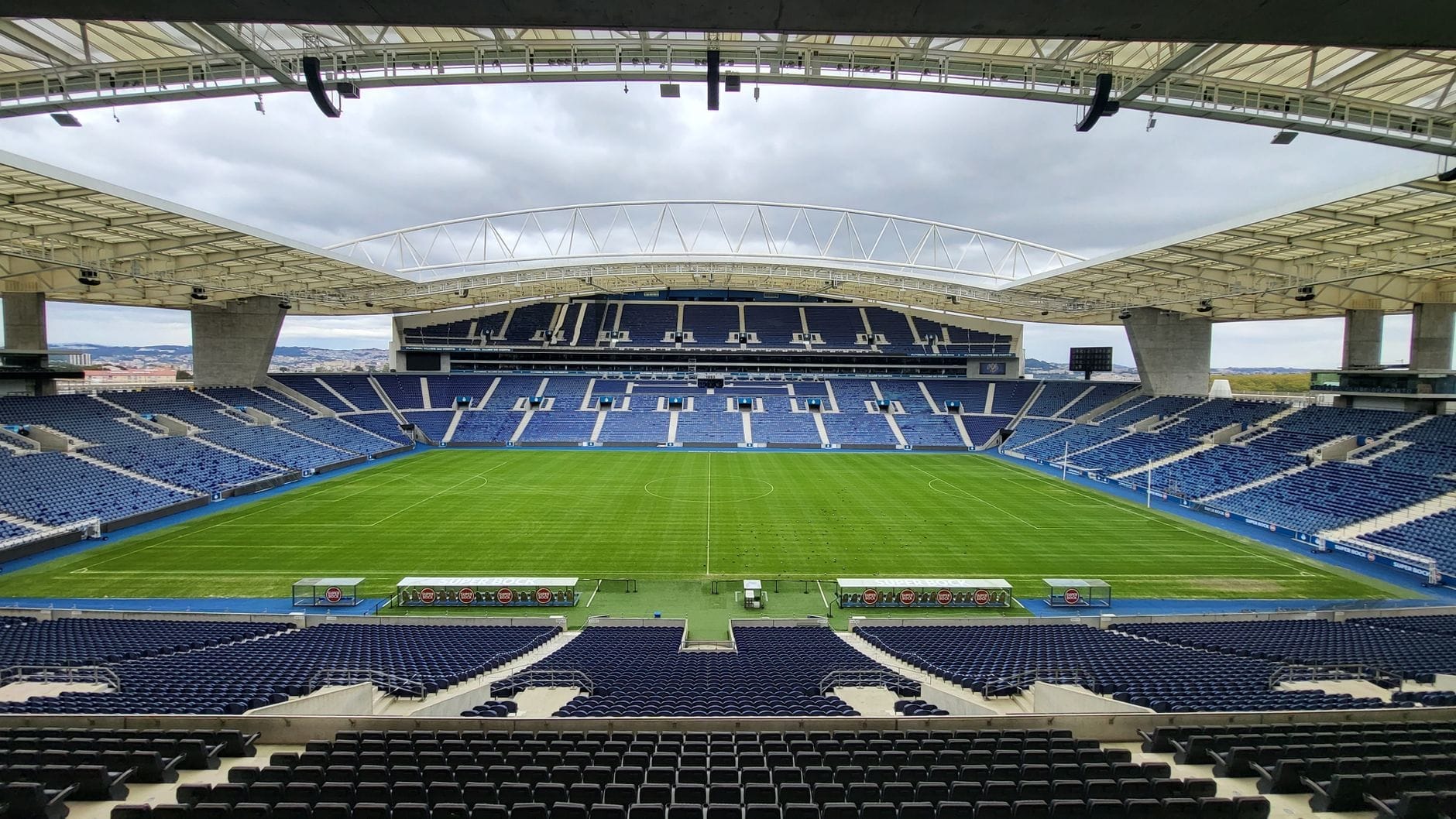 Vista panoramica dell'Estádio do Dragão vuoto con il campo, le tribune moderne e la grande copertura metallica sotto un cielo nuvoloso.