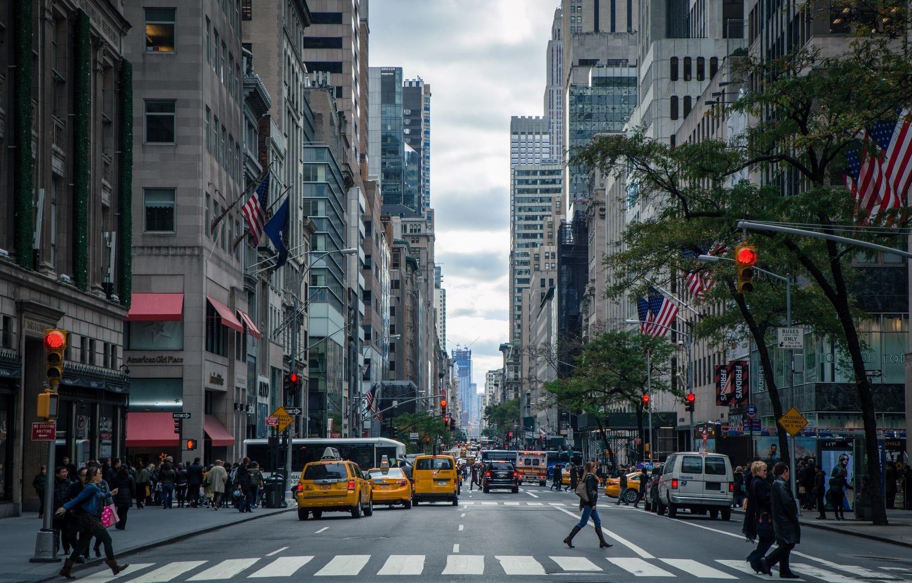 La vivace Fifth Avenue di New York City, con i caratteristici taxi gialli, i pedoni e i grattacieli iconici che fiancheggiano entrambi i lati della trafficata strada.