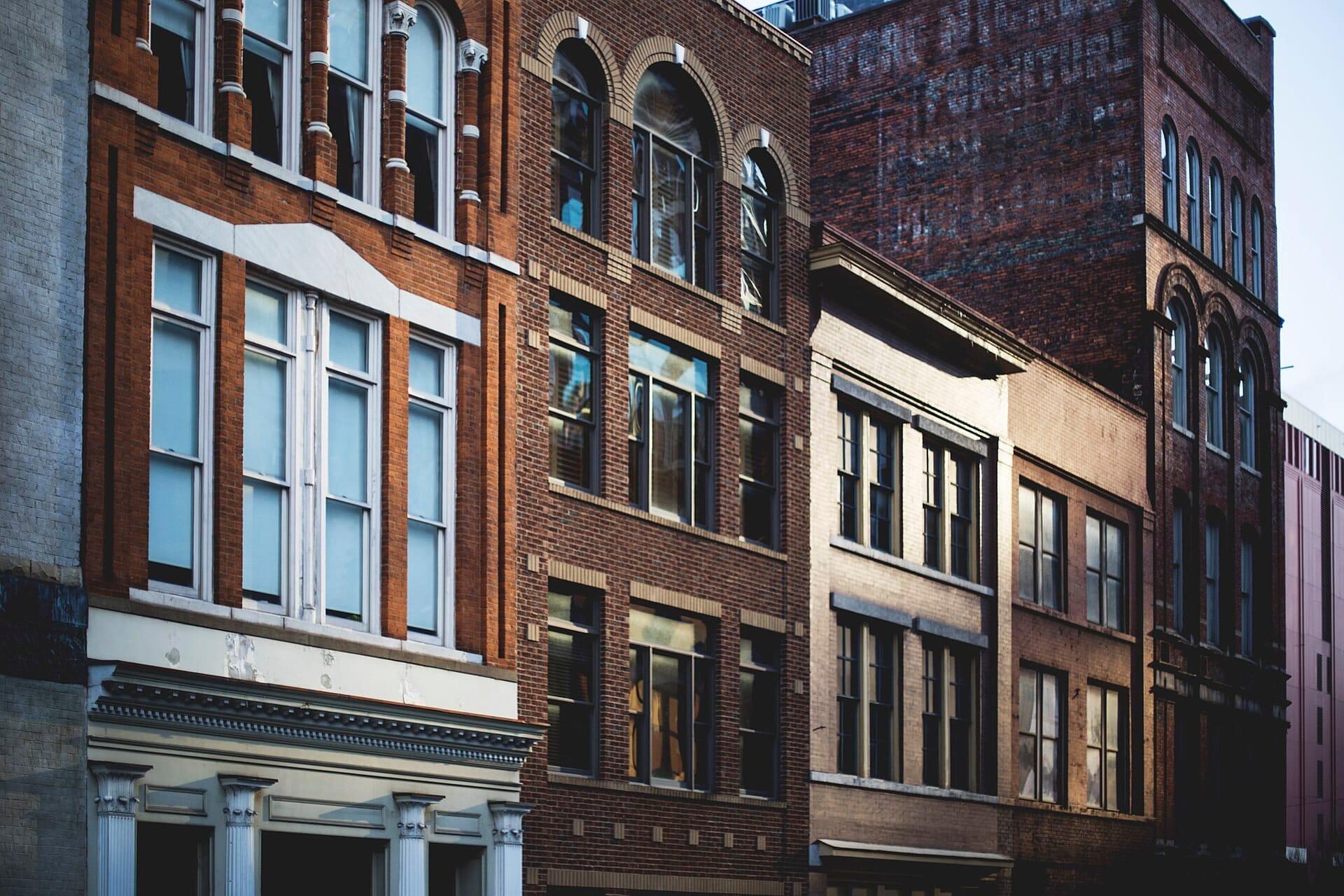 Hileras de históricos edificios de ladrillo con ventanas altas y detalles ornamentados en el barrio Five Points de East Nashville, captados con luz de tarde.
