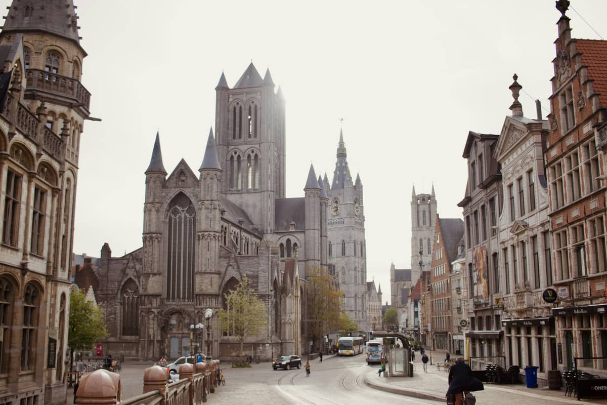 Central Ghent showing Saint Bavo's Cathedral and historic buildings, viewed from the street on a bright, overcast day.
