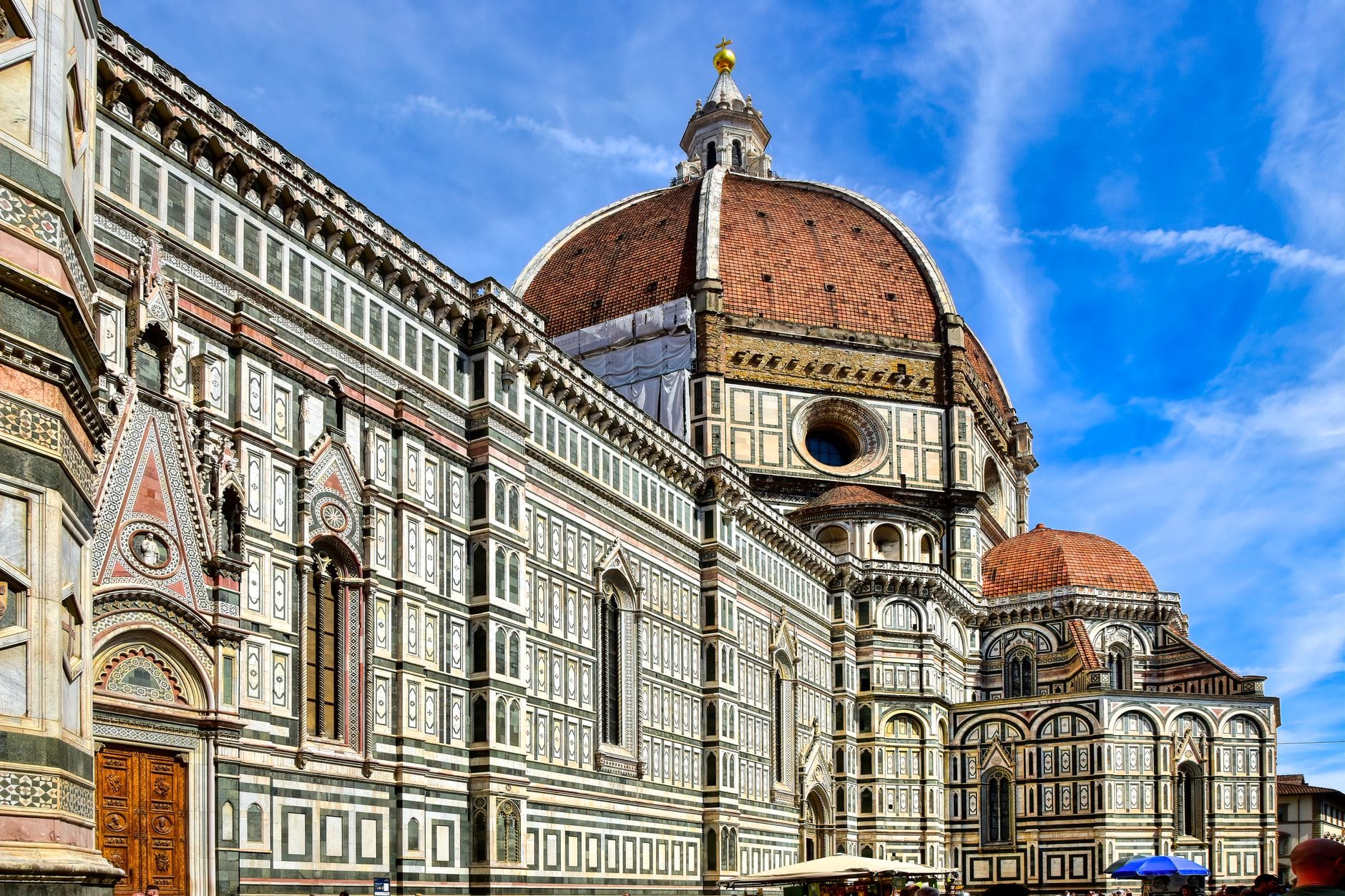วิวมหาวิหารฟลอเรนซ์ (Duomo di Firenze) เห็นโดมหลังคาแดงและผนังหินอ่อนหลากสี เด่นชัดใต้ท้องฟ้าน้ำเงินสด