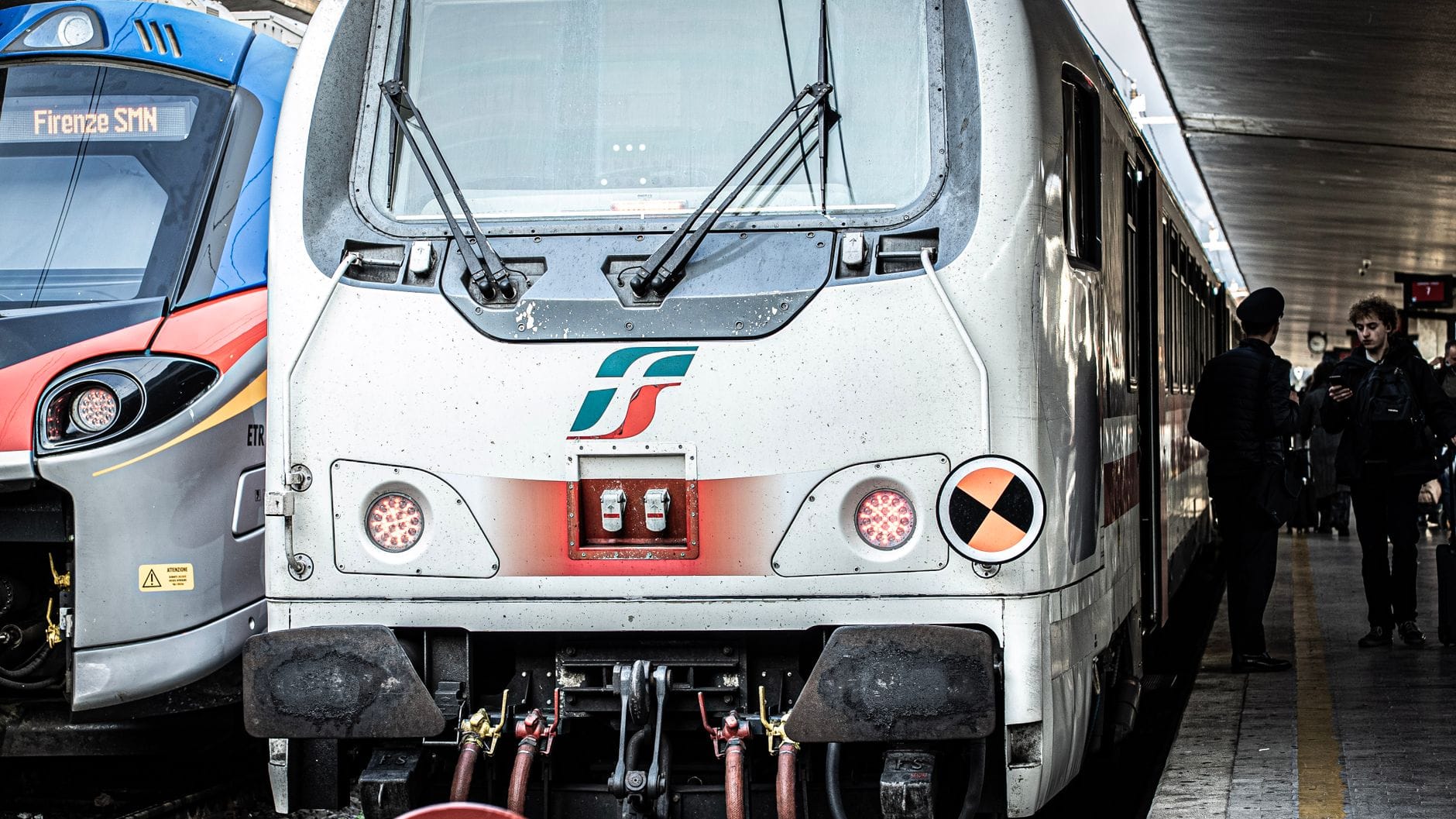 รถไฟอิตาลีที่ชานชาลาสถานี Florence Santa Maria Novella พร้อมผู้คนยืนอยู่ข้างๆ