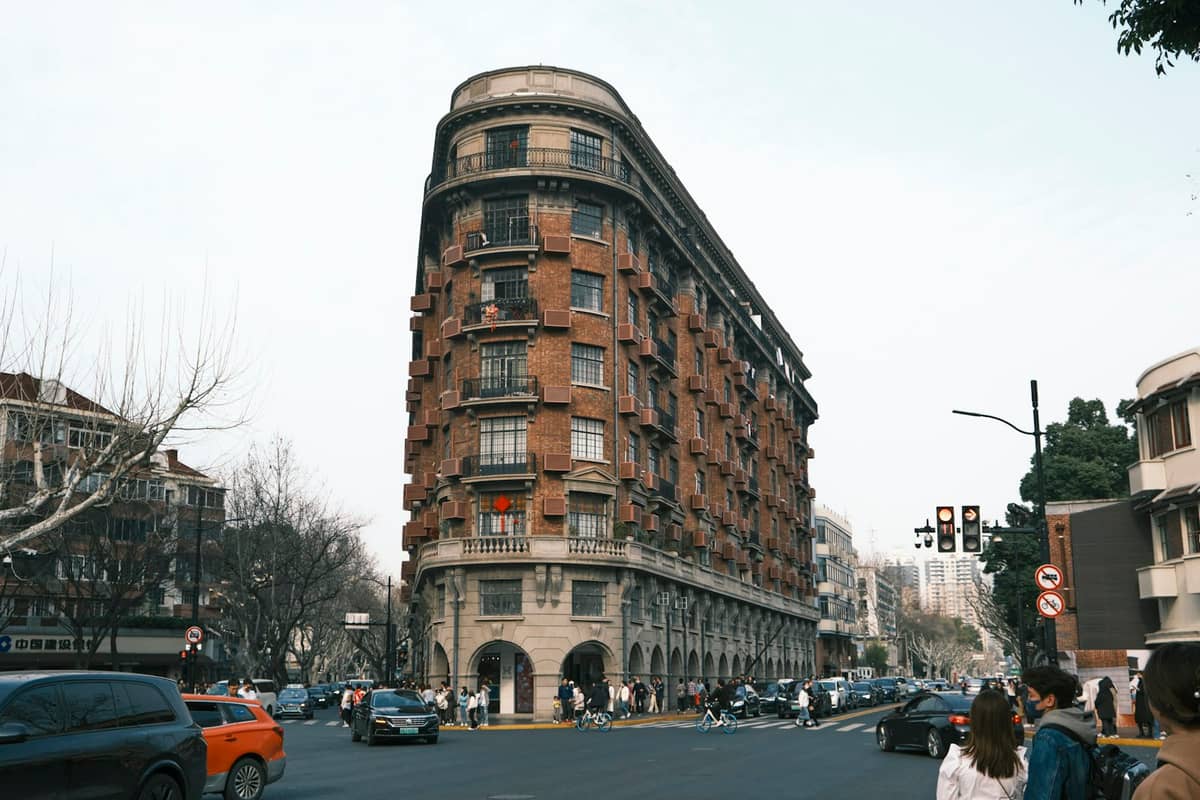 Das historische Wukang Mansion im ehemaligen Französischen Konzessionsgebiet Shanghais mit Architektur aus dem frühen 20. Jahrhundert, baumbestandenen Straßen und lebhaftem Straßenleben.
