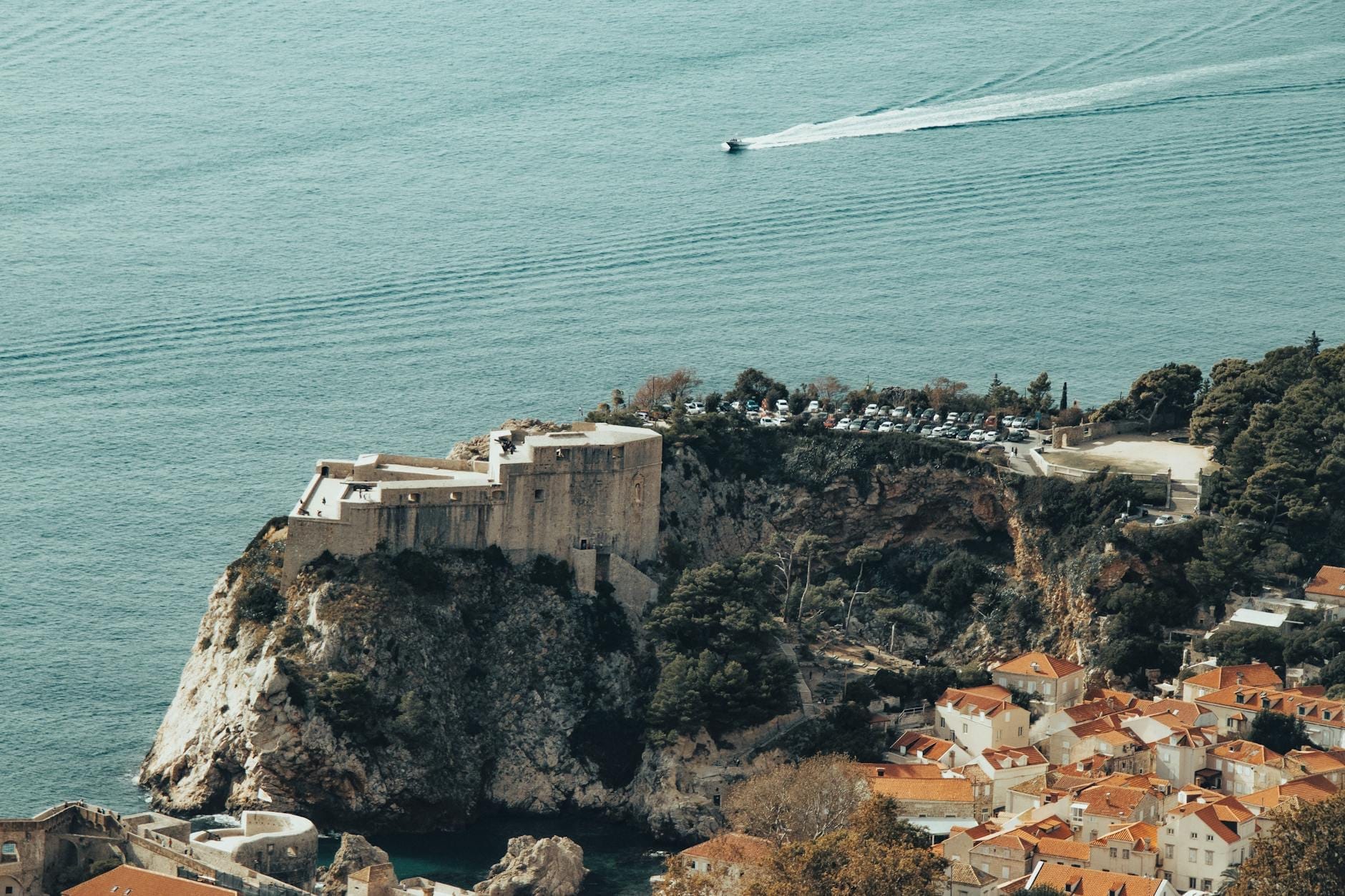 Vista aérea del Fuerte Imperial en lo alto de una colina sobre la ciudad vieja de Dubrovnik y el mar Adriático, con una carretera serpenteante y una costa dramática.