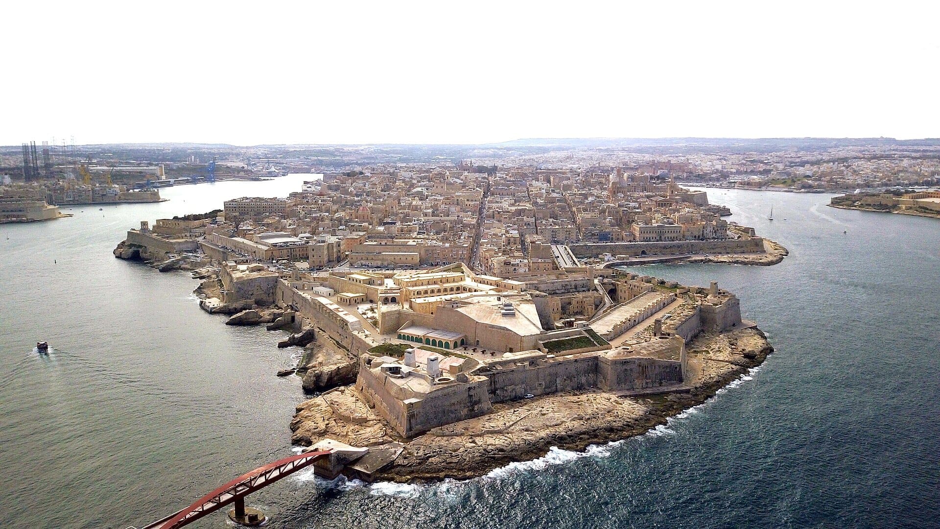 Vista aerea di Fort St. Elmo e del paesaggio urbano storico di Valletta, circondato da lungomare azzurri e bastioni in pietra sulla punta della penisola.