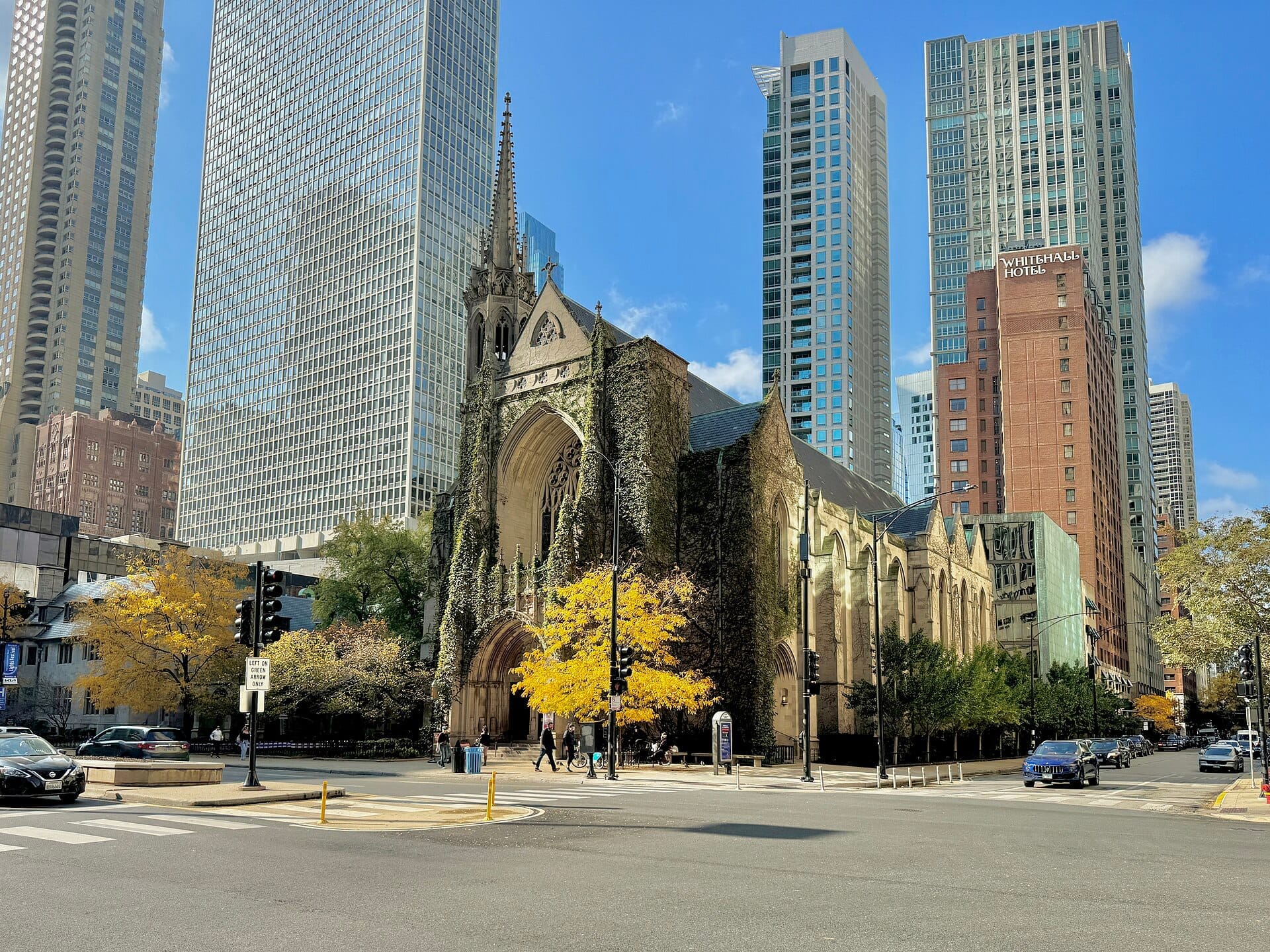 La Fourth Presbyterian Church a Chicago incorniciata da alberi autunnali, con l'architettura gotica che si distingue dai grattacieli moderni circostanti e dal cielo azzurro.