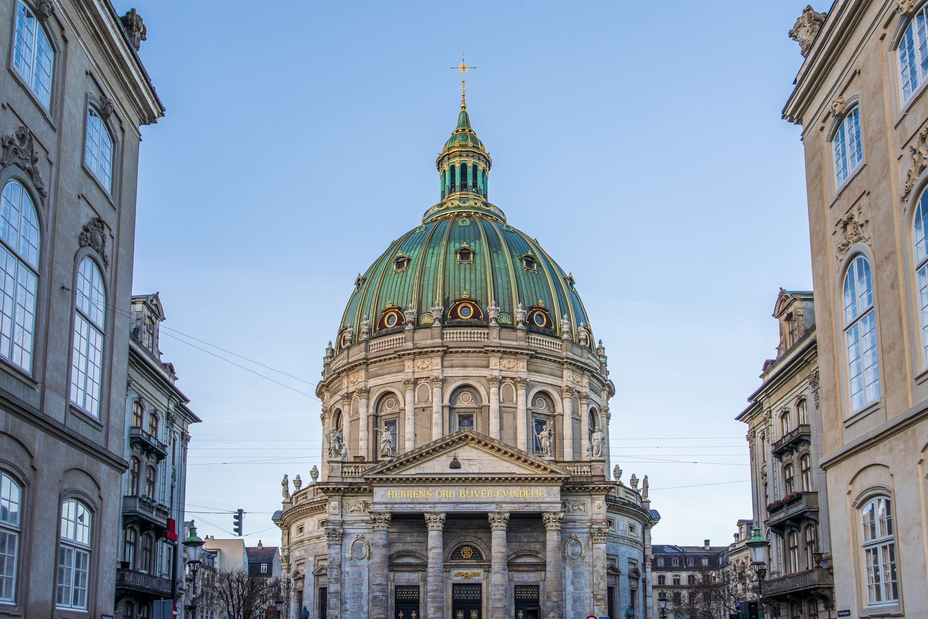La Chiesa di Frederik a Copenaghen con la sua imponente cupola in rame verde che si erge sopra l'ingresso, affiancata da eleganti edifici in una giornata serena.