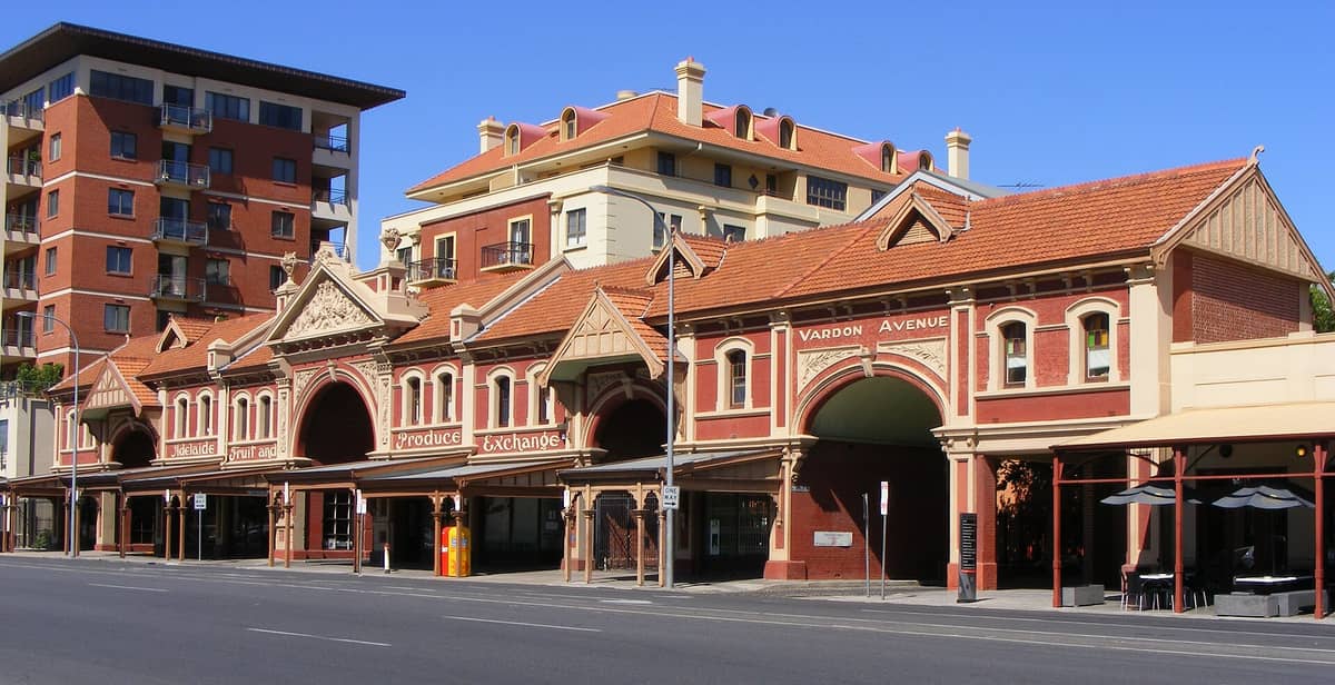 Historisches Adelaide Fruit and Produce Exchange Gebäude mit roten Backsteinbögen, aufwendigen Details und nahegelegenen Stadtapartments an einem sonnigen Tag.
