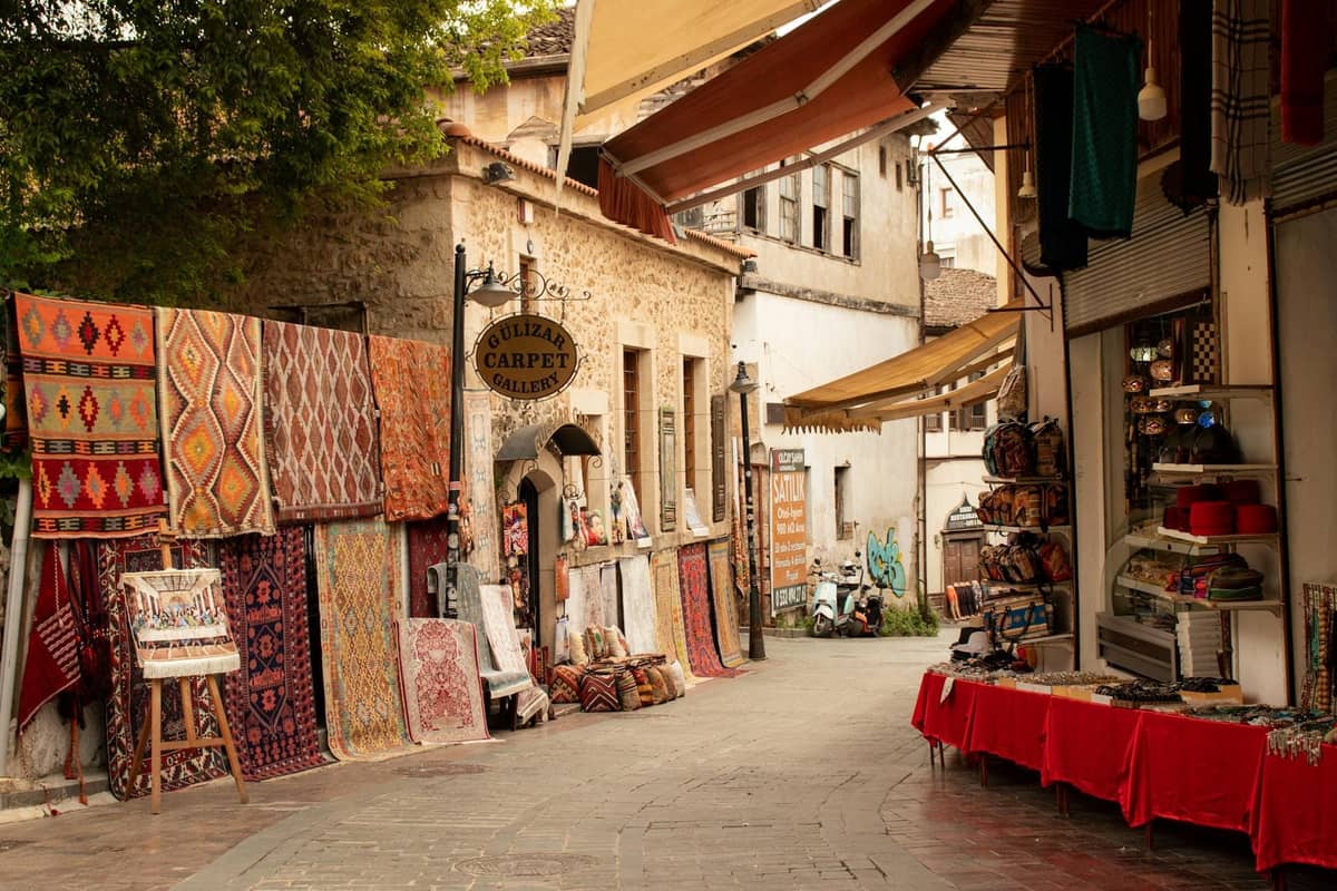 Quaint street in Antalya’s old bazaar with rugs, souvenirs, and historic stone buildings lining the walkway.