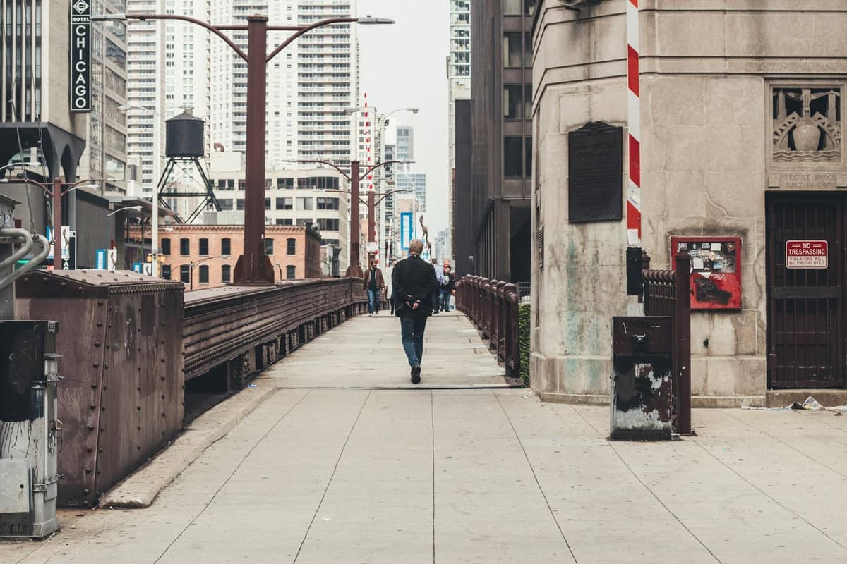 Person, die auf einer Brücke in Chicago läuft, mit Wolkenkratzern und städtischer Architektur im Hintergrund.