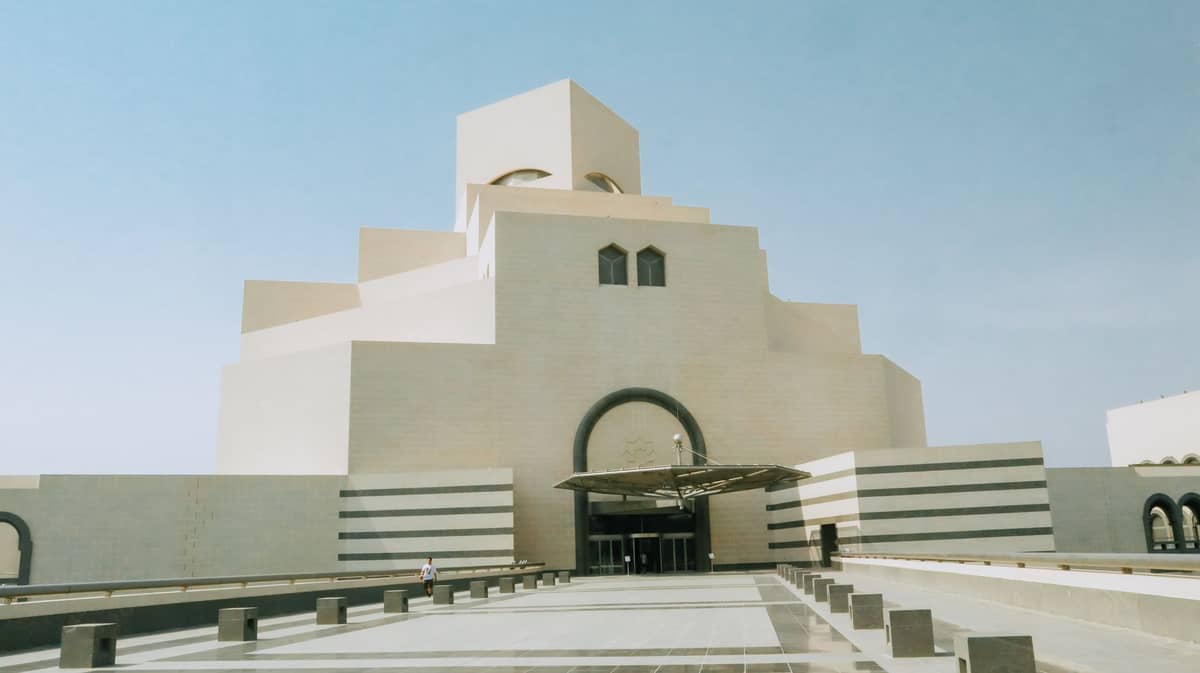 Frontansicht des Museum of Islamic Art in Doha mit markanter moderner Architektur und klarem blauem Himmel darüber.