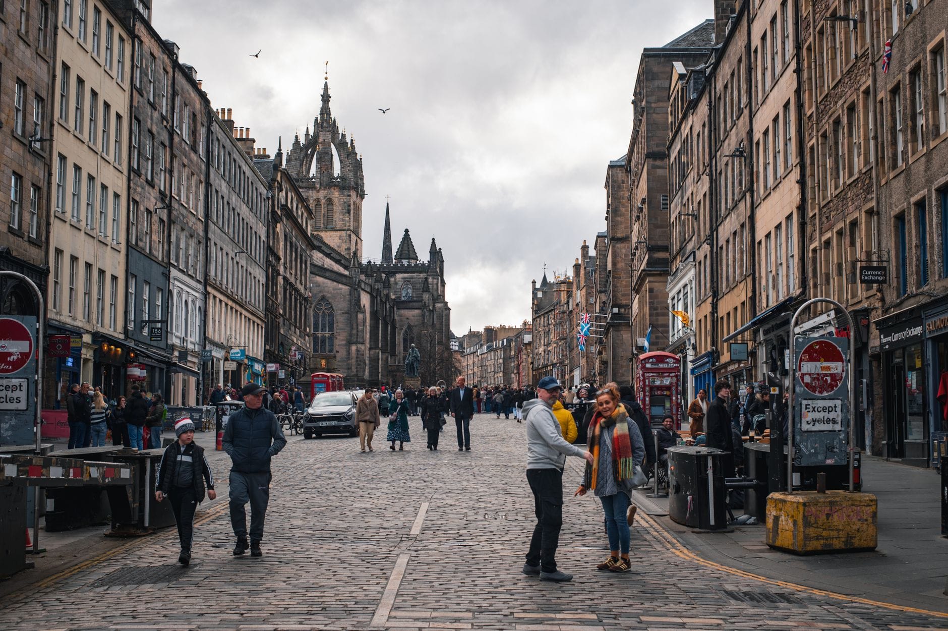 Fußgänger auf der Royal Mile in Edinburgh – einer historischen Straße aus altem Sandstein, im Hintergrund der Turm der St Giles' Cathedral.
