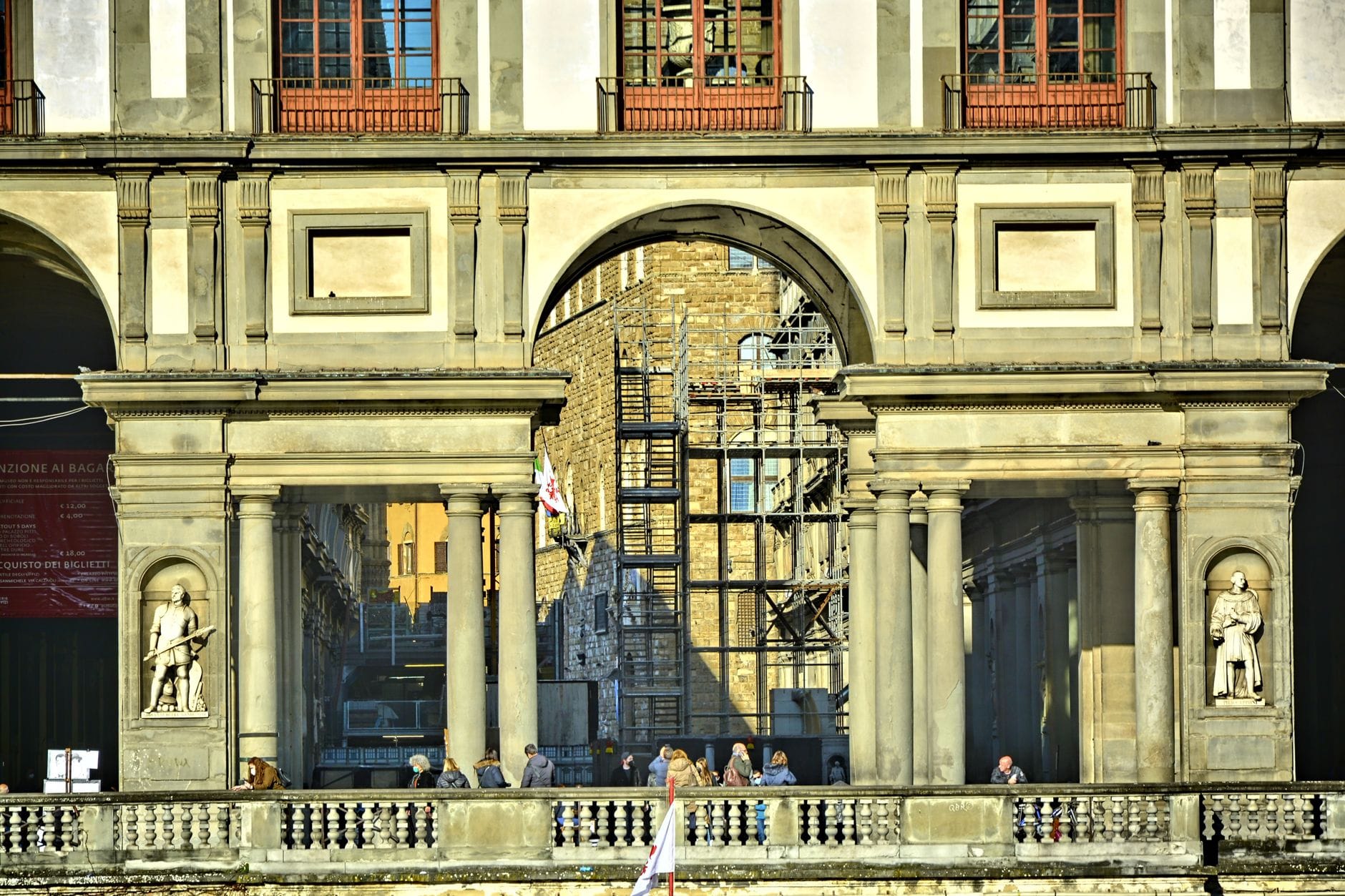ภายนอกของ Uffizi Gallery พร้อมซุ้มเสาและรูปปั้น มีผู้คนยืนเรียงรายตามราวระเบียง ในเมืองฟลอเรนซ์ ประเทศอิตาลี
