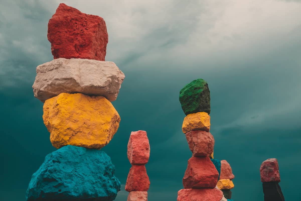 Rocas apiladas y coloridas de la instalación de arte al aire libre 'Seven Magic Mountains' cerca de Las Vegas, con un dramático cielo nublado de fondo.