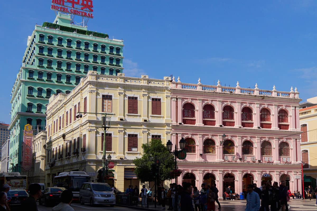 Bunte Kolonialgebäude am Senatsplatz, Macau, mit Passanten und klarem blauem Himmel.