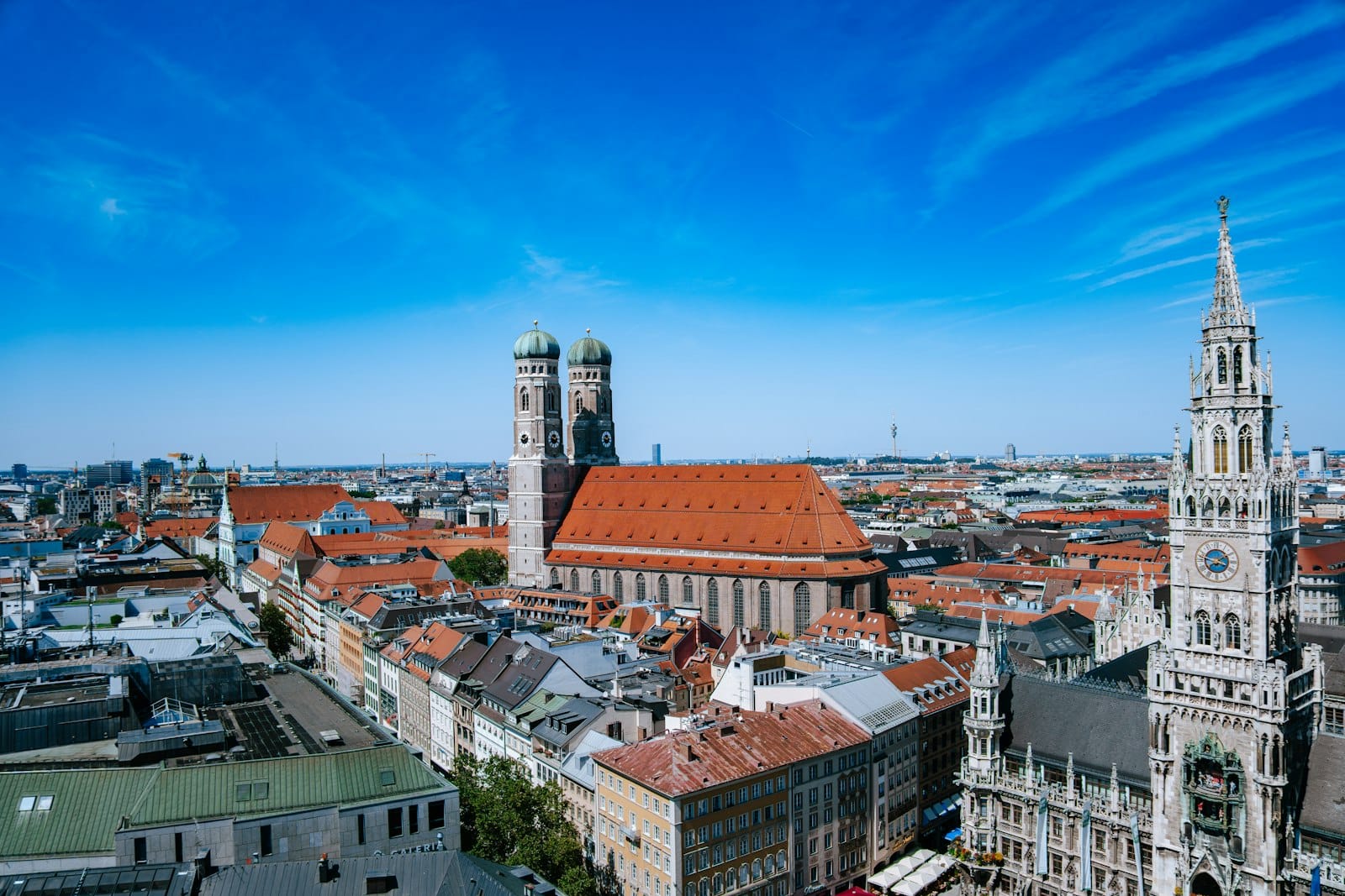 วิวพาโนราม่ากลางเมืองมิวนิก เห็นยอดแฝดของโบสถ์ Frauenkirche และศาลาว่าการเมืองหลังใหม่ ท้องฟ้าสีฟ้าสดใสตัดกับสถาปัตยกรรมโบราณ