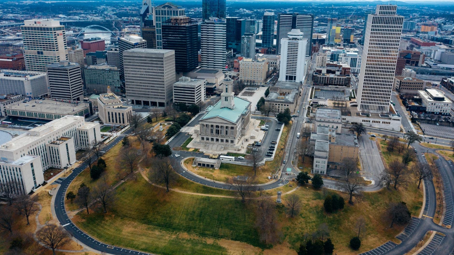 Vista aérea del centro de Nashville con el edificio del Tennessee State Capitol rodeado de monumentos de la ciudad y espacios verdes.
