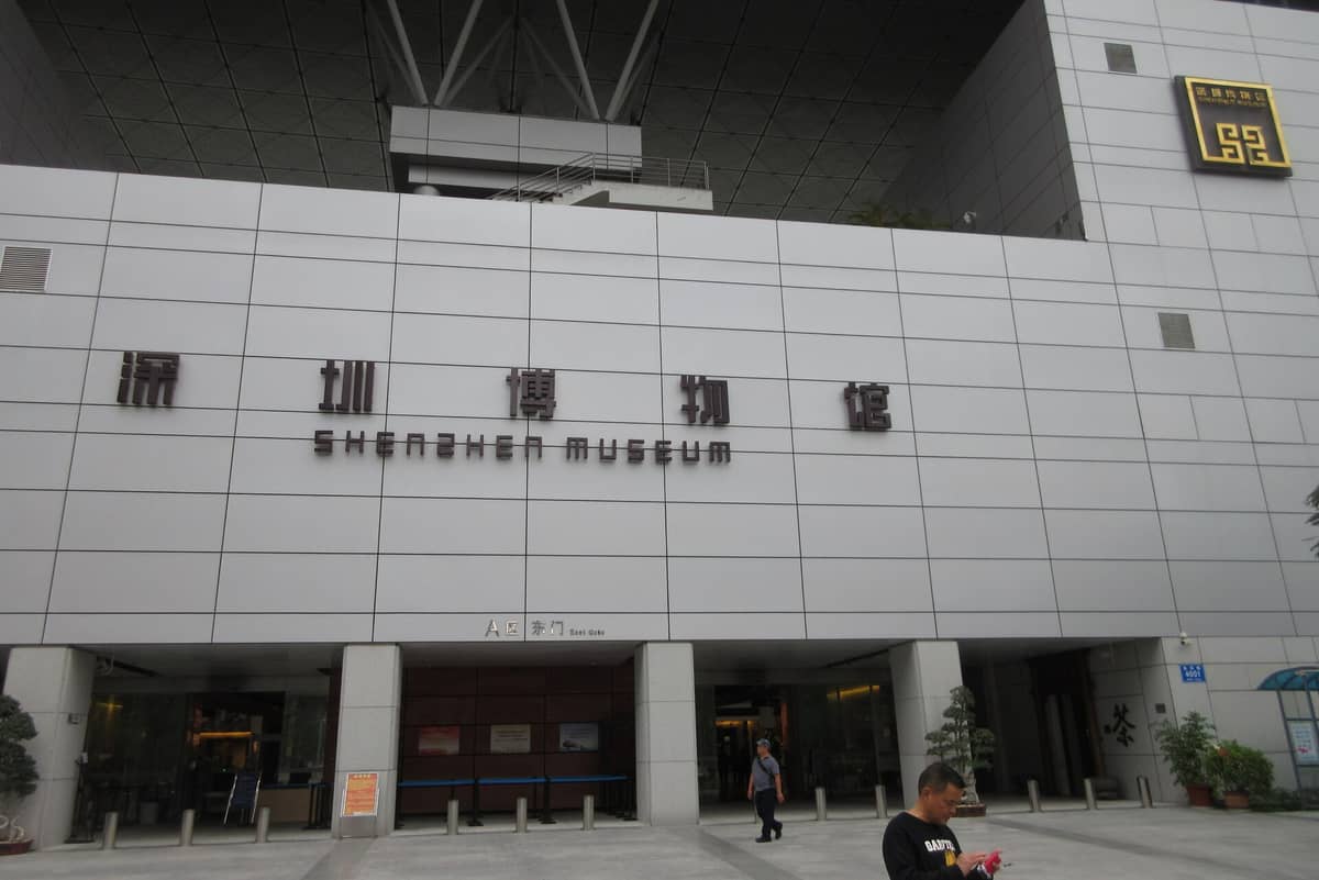 Entrada principal do Shenzhen Museum, com seu nome em grandes letras chinesas e inglesas em um edifício moderno