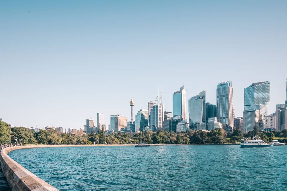 View of Sydney skyline from the Royal Botanic Garden, with lush greenery along the harbourfront and city skyscrapers in the background.