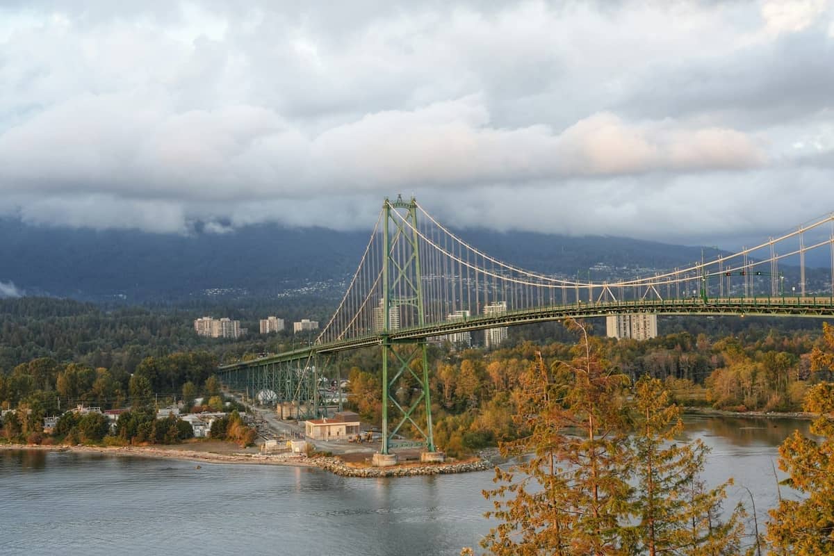 Lions Gate Bridge ในแวนคูเวอร์มองจากด้านบนพร้อมต้นไม้ในฤดูใบไม้ร่วงและภูเขาเป็นฉากหลัง
