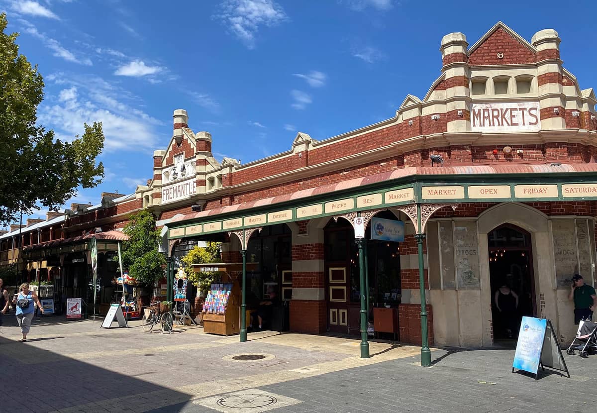 Außenansicht des historischen Fremantle-Markets-Gebäudes mit Passanten unter strahlend blauem Himmel in Fremantle, Westaustralien.