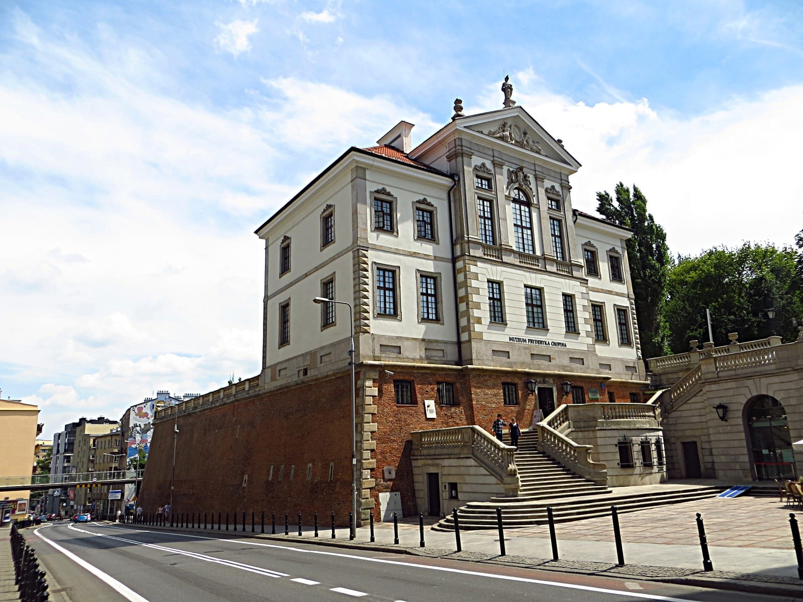 อาคารพิพิธภัณฑ์ Fryderyk Chopin ในกรุง Warsaw เป็นพระราชวังหินขาวและอิฐอันสง่างาม พร้อมบันไดขนาดใหญ่และรายละเอียดทางสถาปัตยกรรมแบบคลาสสิกใต้ท้องฟ้าสีฟ้า